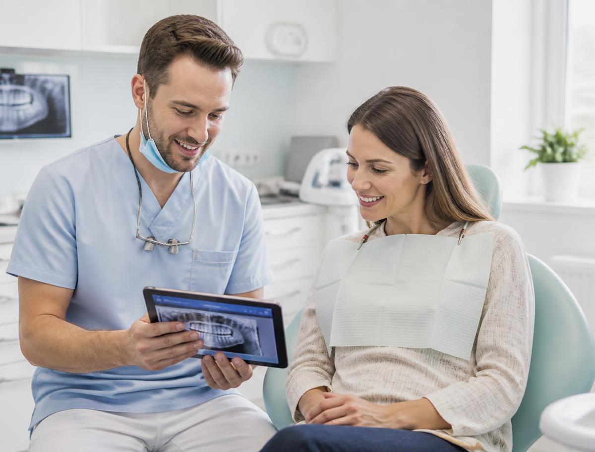 Dentist showing dental x-rays to a patient on a tablet